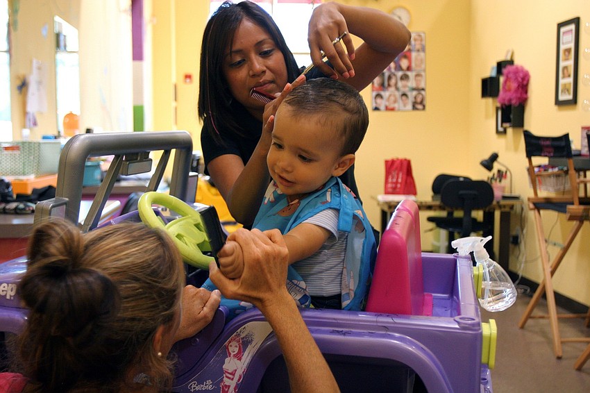Reid Sokol, 1 years-old, tries to brush his mom's hair as he gets his first hair cut by Gladis Santana Monday, June 13 at Lilâ€™ Divas and Dudes.