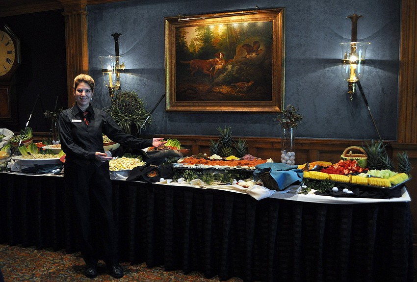 Izabella Davison, one of the servers at the Oaks Club, shows off one of the many tables of food she designed and put together for the Father's Day Brunch Sunday, June 19 at the Oaks Club.