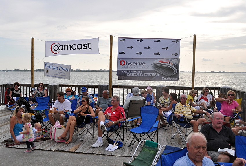 People sitting on the deck by the water behind the Van Wezel Friday, July 15 at Friday Fest.