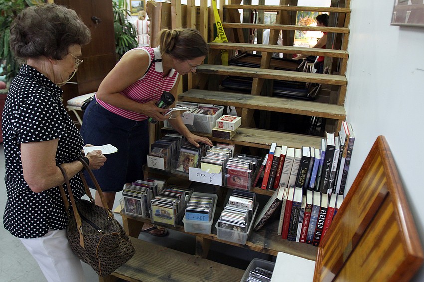 People browsing through a variety of CDs, many of them being Christmas CDs.
