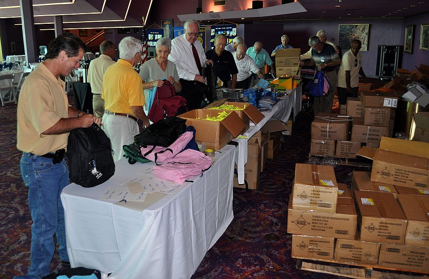 Rotarians make their way down the line filling up one to two backpacks at a time Tuesday, Aug. 16 at the Van Wezel.