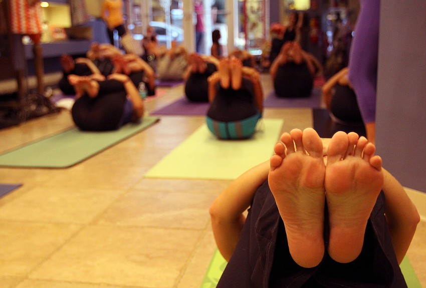 People hold their feet up and roll on their backs during yoga Friday, Aug. 26 during Vinyasa & Vino at T. Georgianos.