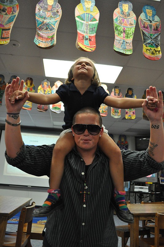 Ava Gracia, 5, got a closer look at student artwork atop the shoulders of her friend, Lo Robertson.