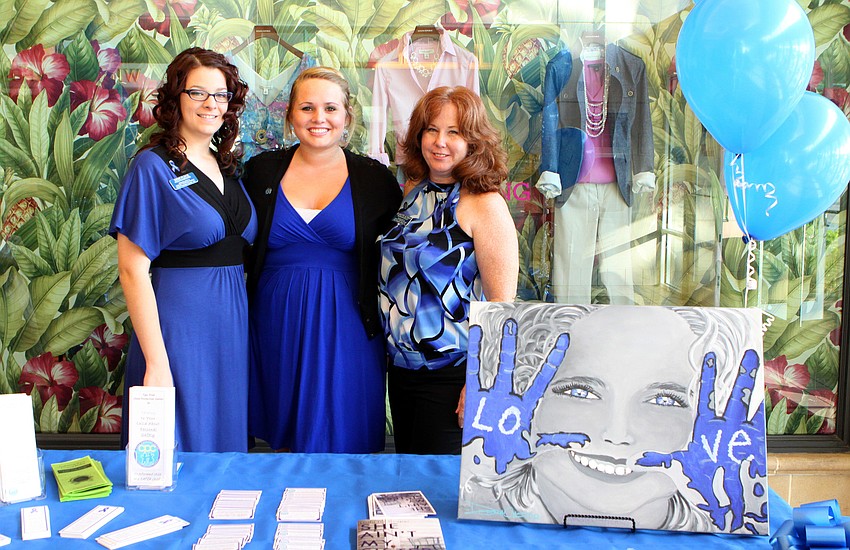 Mimi Fleck, intern Kailey Williams and Jeanette Altman of the Child Protection Center pose behind their booth Thursday, April 28 during the Paint the Town Blue event at Westfield Southgate.