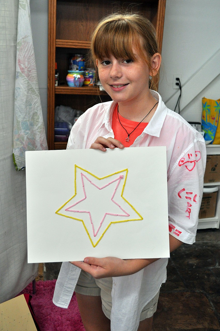 Alexis Seyer, 10, shows off her star string art project that she made earlier in the week.