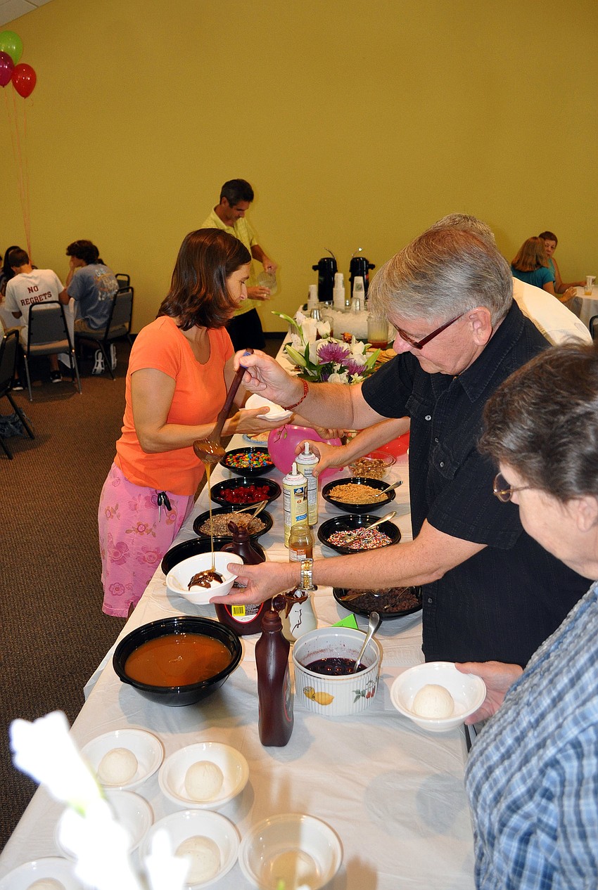 People line up to dress up their bowls of ice cream with chocolate sauce, caramel sauce and other toppings.