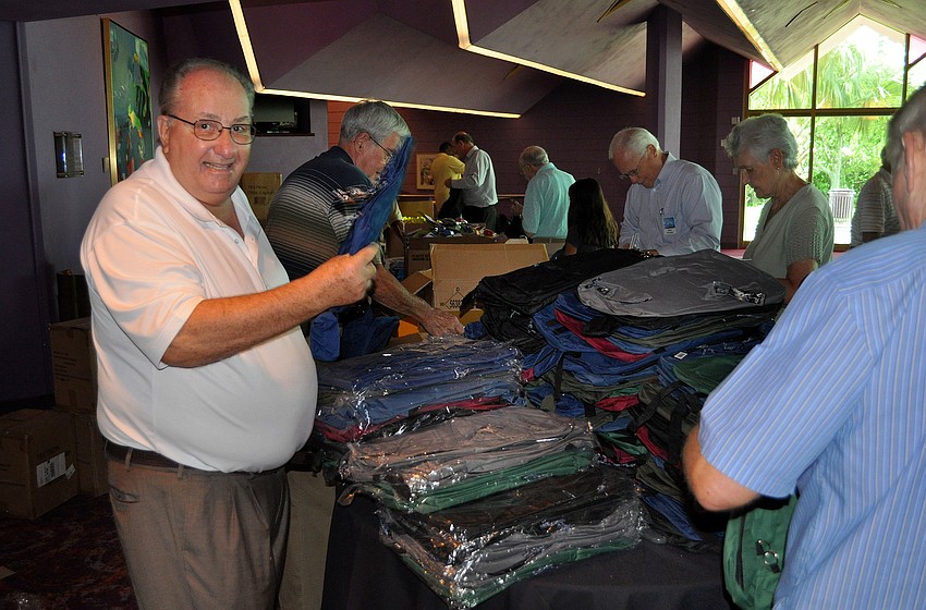 Bill Folz unwraps new backpacks for people to fill up with school supplies.