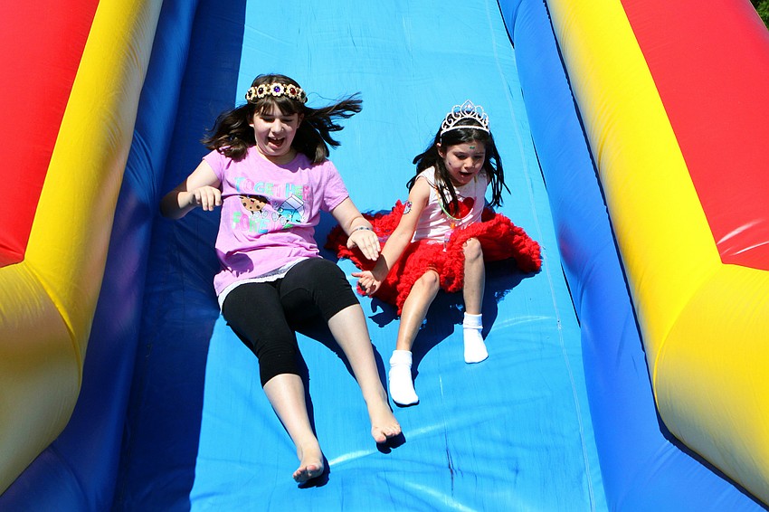 Emma Diner, 11, and Riley Silver, 6, slide down the bounce slide on Sunday, March 20 at Temple Emanu-El's Purim Carnival.