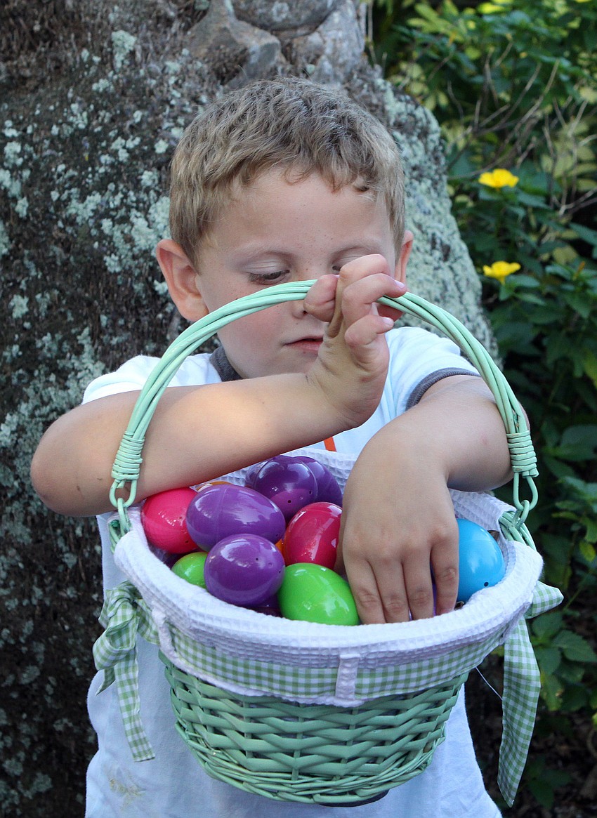 Kyle Petrin reaches into his basket to find the big egg he got while Easter egg hunting at Mar Vista.