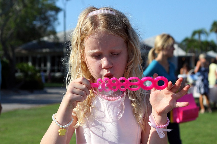 Tatum Blair, 6, blows bubbles to pass the time before the Easter egg hunt.