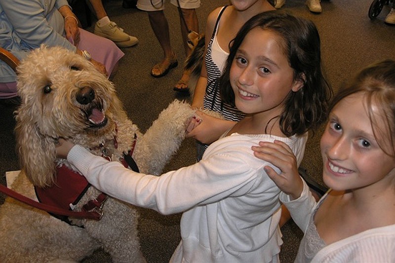 East County sisters Audrey and Abby Lipton greet a pet therapy dog during a nursing home visit.