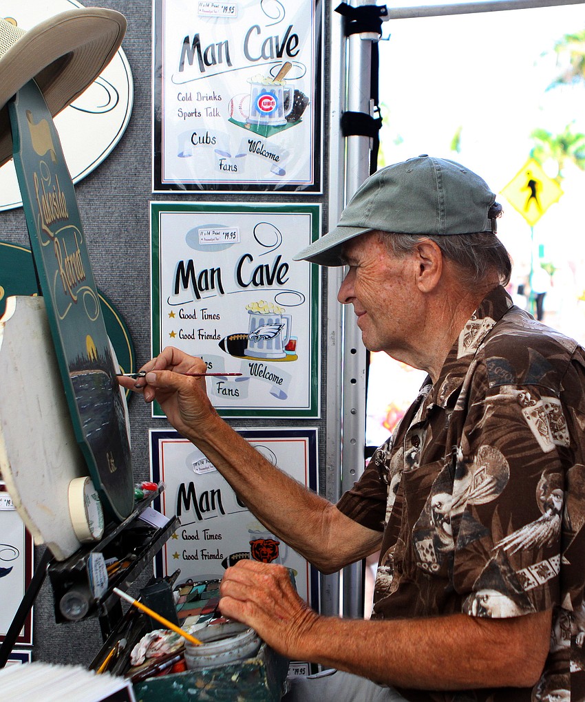 Robert Mefford works on painting one of the many wooden signs he makes and sells during the Craft Festival Sunday, May 22 along Main Street and in Five Points Park.