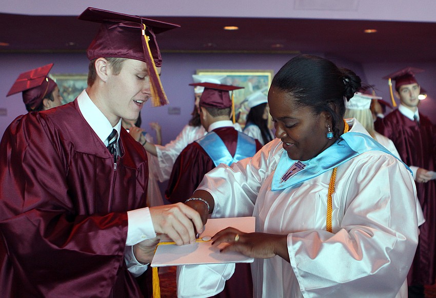 Tim McGrail tries to help Reyna St. Louis with her cap and tassel Friday, May 27 at the Van Wezel Performing Arts Hall.