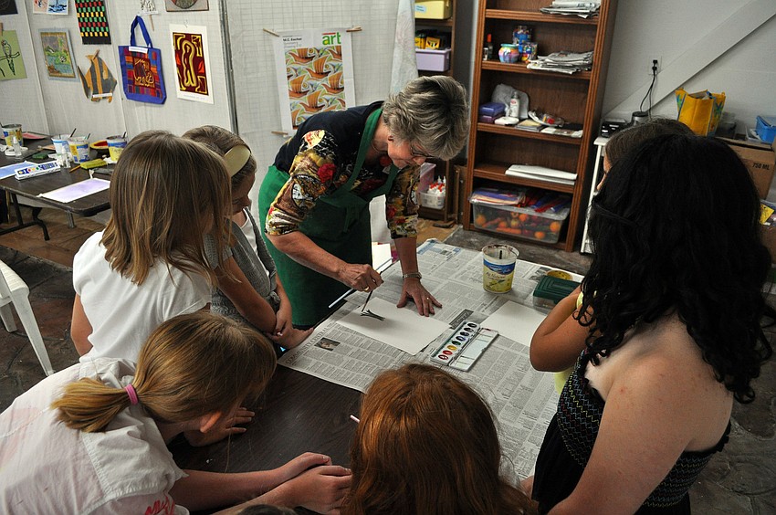 The class gathers around a table to watch their instructor, Charlotte Smith, teach them how to do the next art project Friday, July 8 at the Art and Photography Studio of Colleen Cassidy.