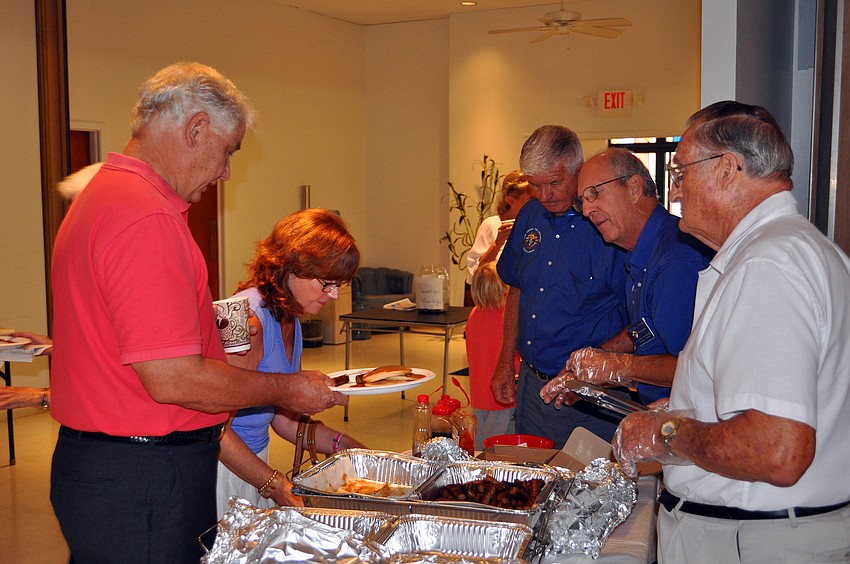 People in line for biscuits, sausage, pancakes, donuts and coffee.