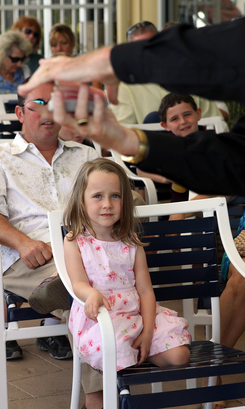 Alyse Martin keeps her eyes on the cards that magician Stevie Dee shuffled during the magic show Sunday, April 24 at Bird Key Yacht Club's Easter celebration.