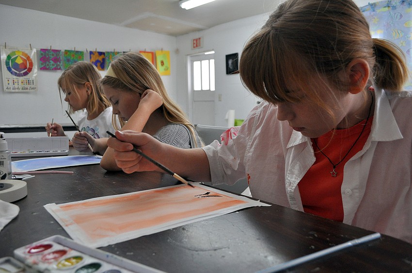 Isabella Thomsen, 9, Anna Parish, 9, and Alexis Seyer, 10, work on creating their tree paintings with their water colors, paint brushes and by blowing through a straw.