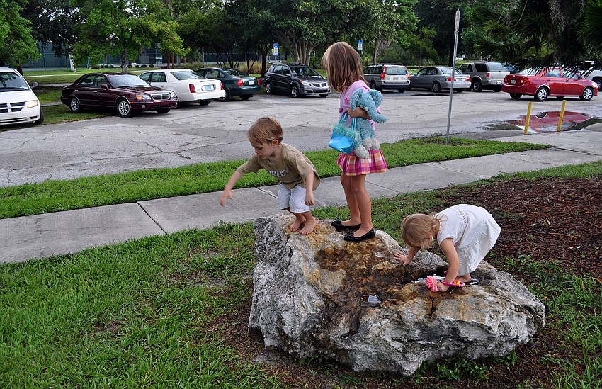 Bodhu Kirschner, 3, Rowan Lee, 4, and Selby Kirschner, 2, play on a rock at Payne Park.