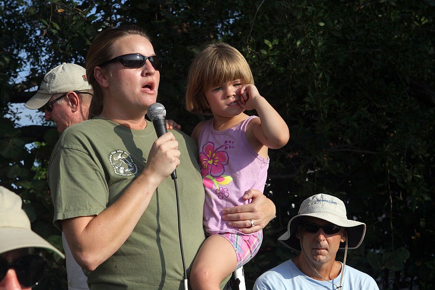 Sarah Stephenson of Florida Fish and Wildlife talks to the crowd about the importance of scallops while holding her daughter, Danielle, 4, Saturday, August 13 during the 4th Annual Sarasota Bay Great Scallop Search.
