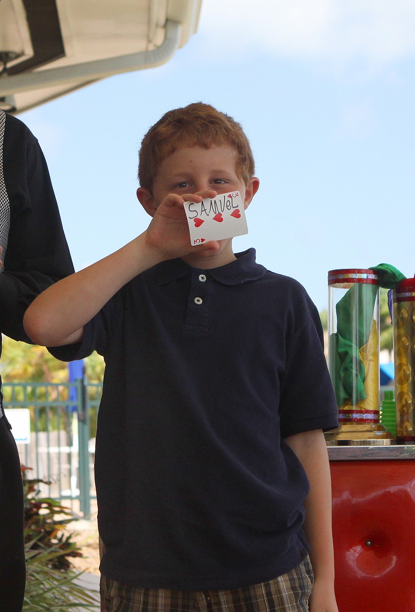 Samuel Shupin shows the crowd the playing card that he wrote his name on for a magic trick.