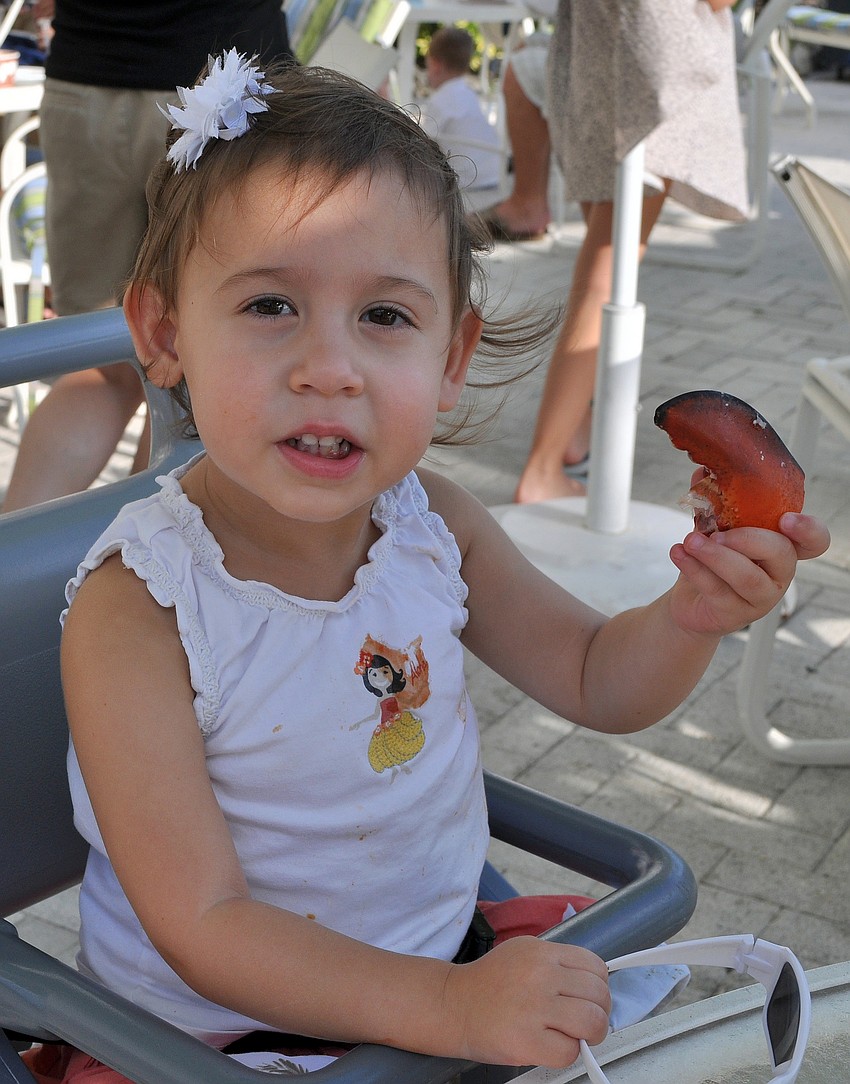 Caitlyn Drizos, 2, shows off a lobster claw Sunday, July 3 at the Lobster BBQ by the pool at Longboat Key Club Resort.