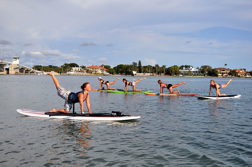 Michelle Young, Christina Zash, Lynne Orlando and Nina Schmidt follow Ami French during a yoga paddle boarding class, Thursday, June 23 out at New Pass Park.