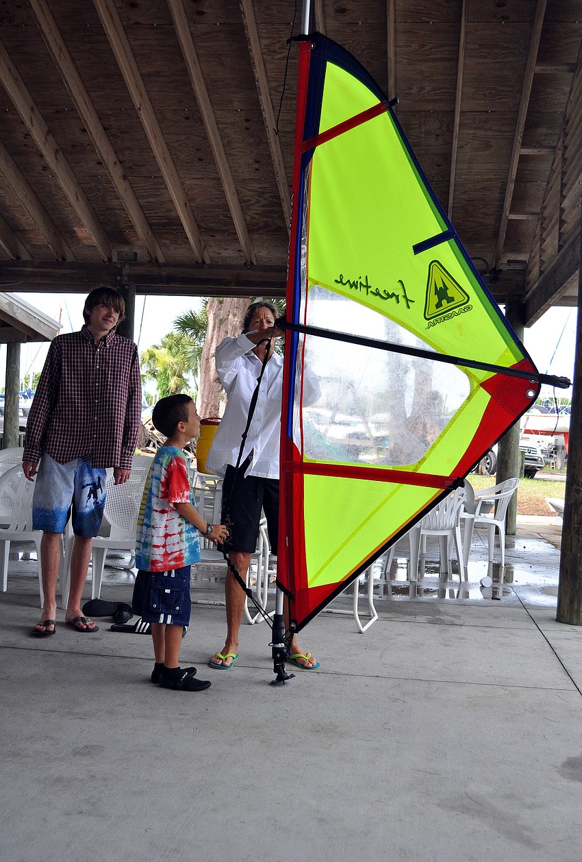 Laurel Kaiser tries to make the sail the right size for Jeffrey Rosenthal, 8, Friday, July 8 during the Island Style Water Sports Camp.
