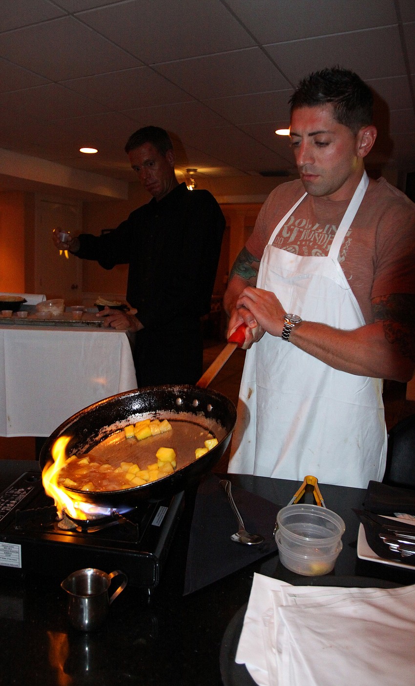 Brian Juliano dips his skillet into the flame in order to make the flambÃ© dessert.