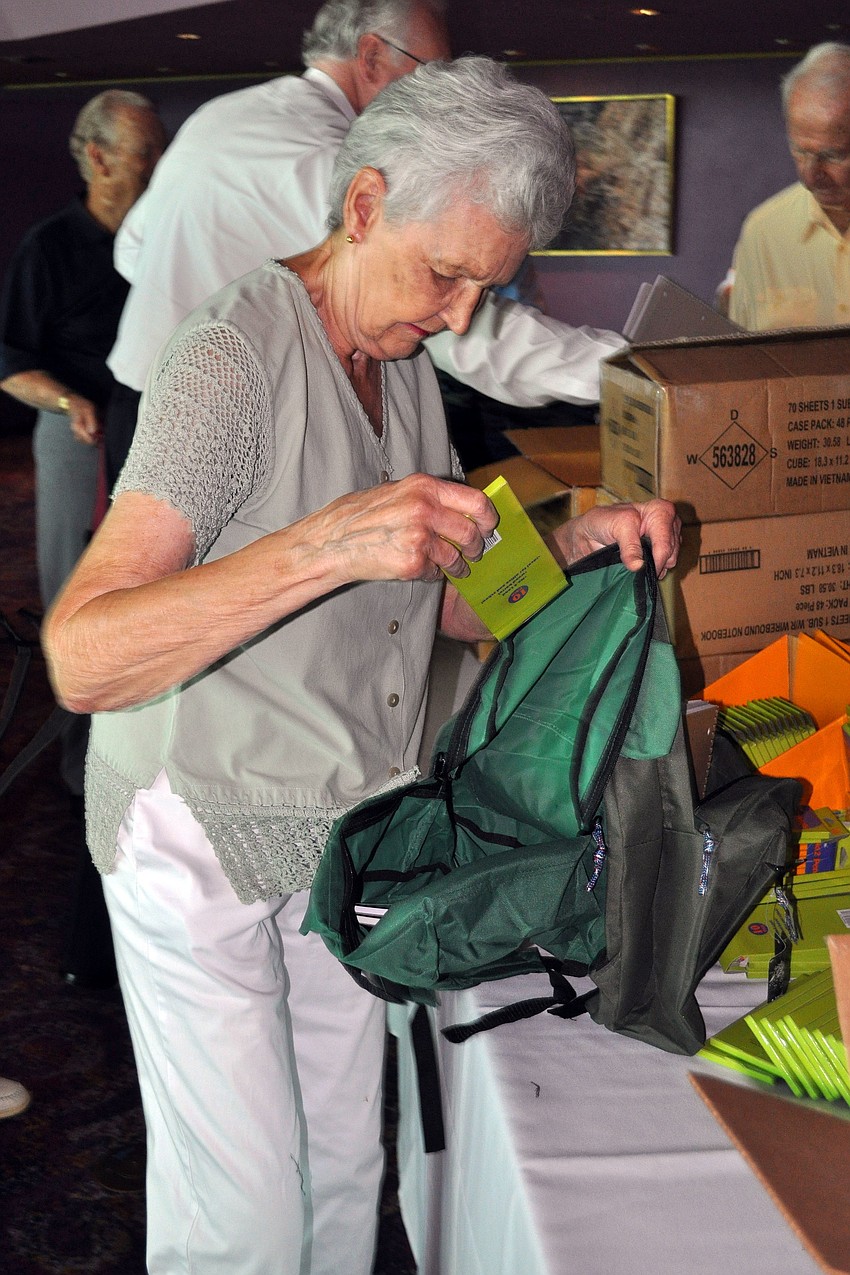 Greta Mahaffey adds a pack of 10 No. 2 pencils into a green backpack.