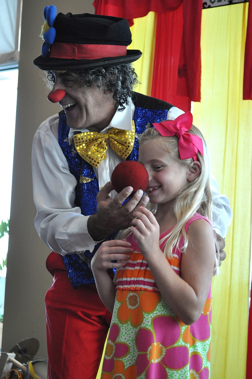 Spaghetti the Clown adds a clown nose to Olivia Miller's nose.
