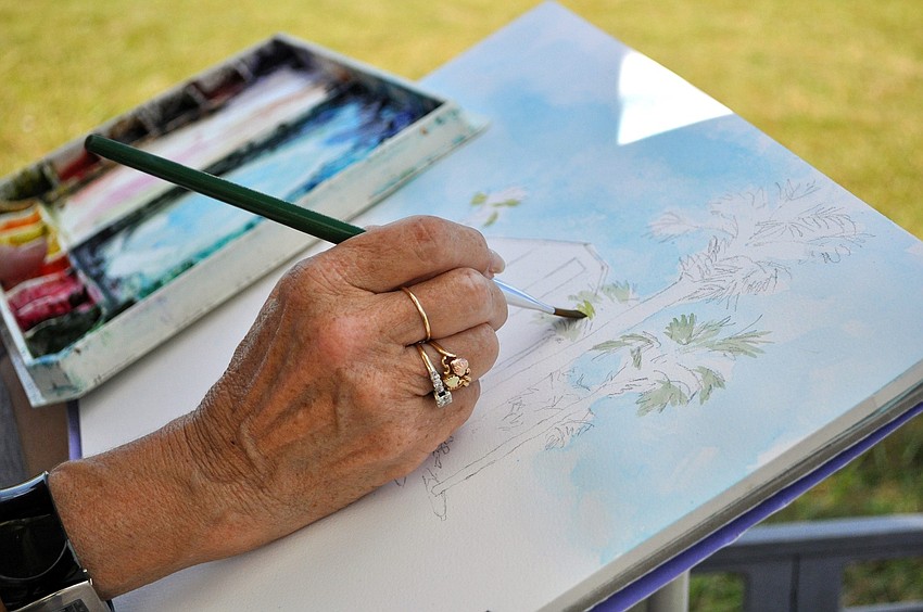 Marilyn Offer paints in the palm trees on her canvas Wednesday, June 22 out in the grass by Siesta Key Public Beach. Offer says that Siesta is her favorite place to paint.