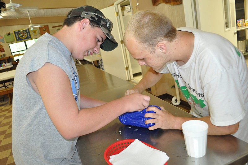 Camper Chris Plaia, 14, and counselor Jeff Andacht worked on removing a label from a bottle.