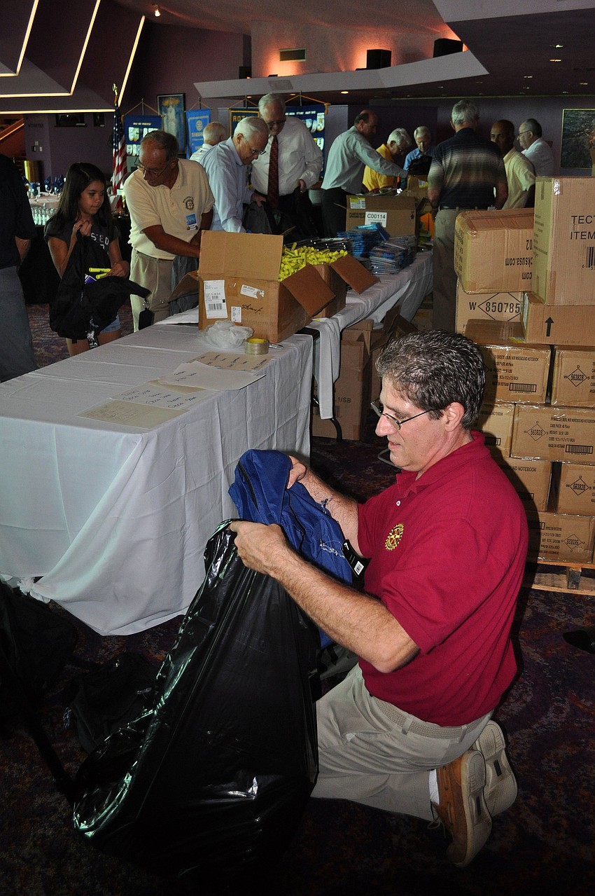 Keith Millard counts out loud as he adds filled backpacks into a garbage bag Tuesday, Aug. 16 at the Van Wezel.