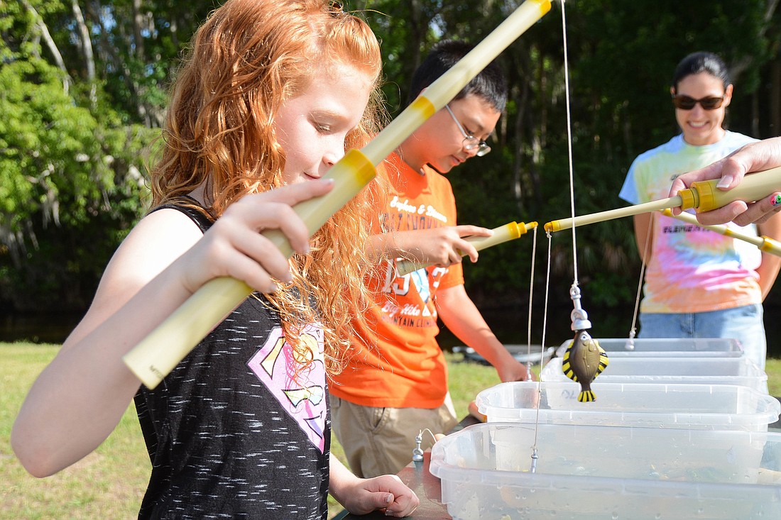 Old Kings third-grader Gianna Seifert, left, plays a magnet fishing game during the school's bass release. Photo by Paige Wilson