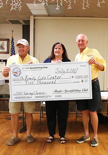 Flagler Sportsfishing Club directors, Mike Crotts (left) and Chuck Radloft (right) present a $5,000 check to Family Life Center Finance Director Tammy Sanner on July 11. Photo by Paige Wilson