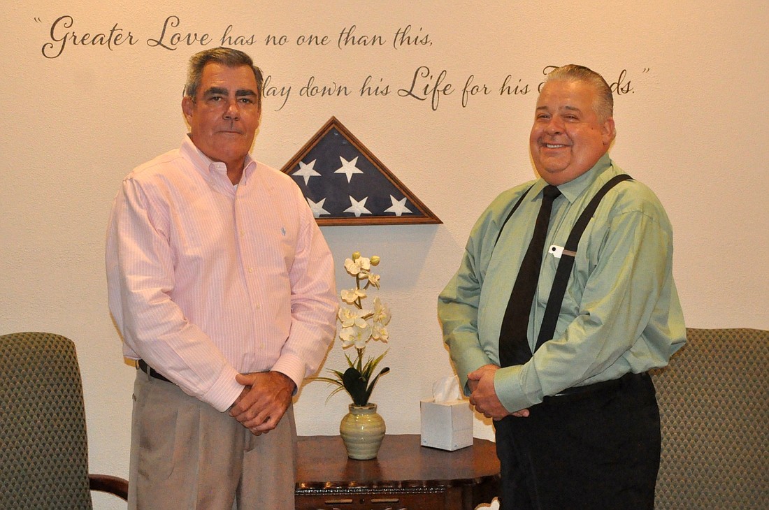 Tony Chambery (left) and Paul Chambery stand in front of the funeral home's wall dedicated to the deceased from the military and law enforcement. Photo by Ray Boone