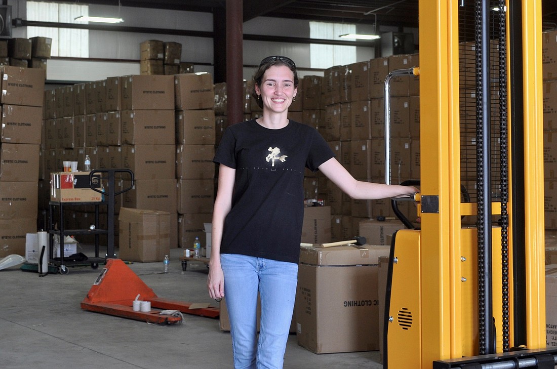 Ashley Vannoy, the CEO of Alexander Del Rossa, stands in the front entrance of her warehouse. The warehouse receives about 80 semi-truck loads of clothes each year. Photo by Ray Boone