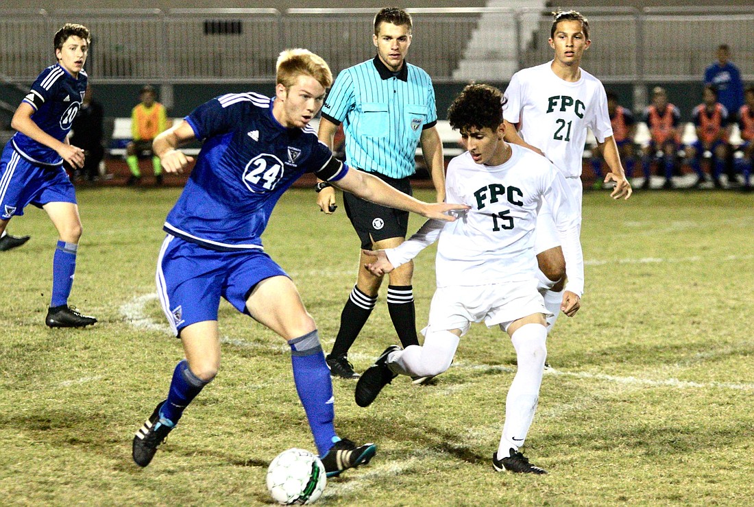 The Pirates' Nathan Hubbs dribbles the ball against an FPC defender. Photo by Ray Boone
