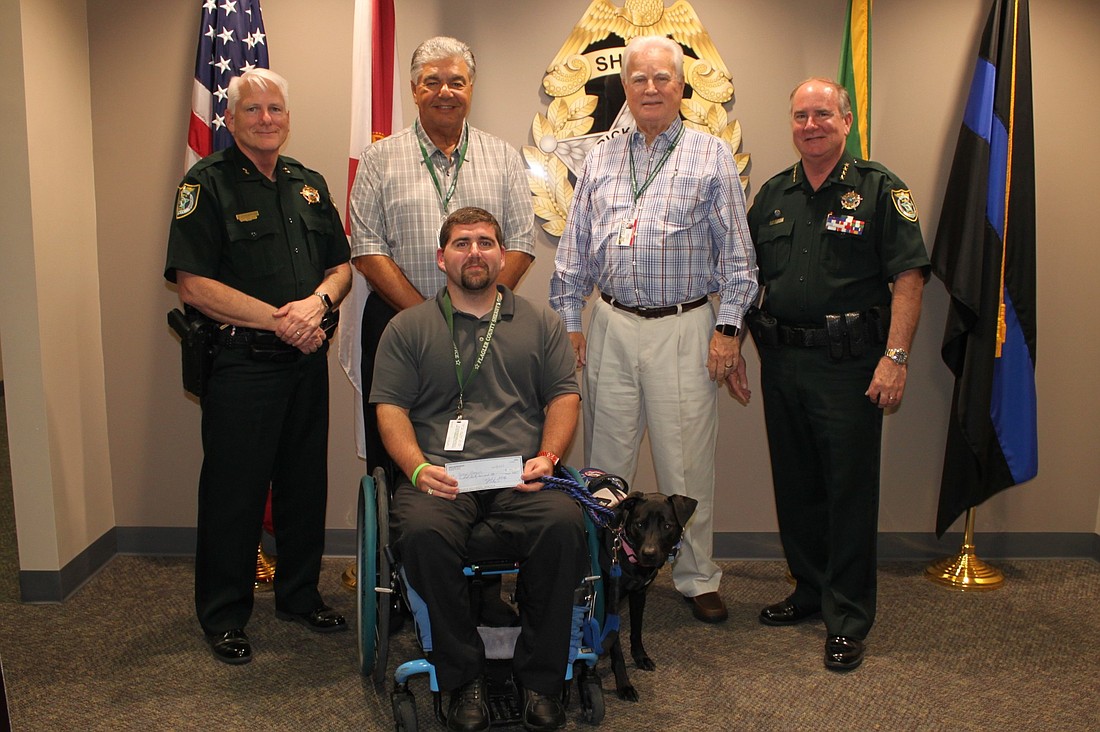 Detention Deputy Stephen Watkins receives a check from the FSEAT to pay for his new wheelchair. Photo courtesy of the Flagler County Sheriff's Office