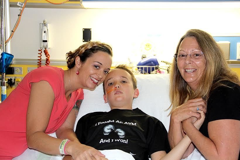 Ashley Higgins and Grandma Tana Fraser with Cameron in the hospital. Cameron is wearing a T-shirt especially designed for him. It says "I fought an AVM and I won." Phot by Jacque Estes