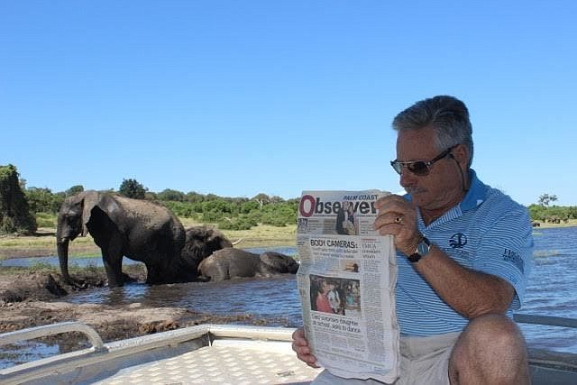 Manuel Carneiro reads his Palm Coast Observer on the Chobe River in Kesane, Botswana. Courtesy photo