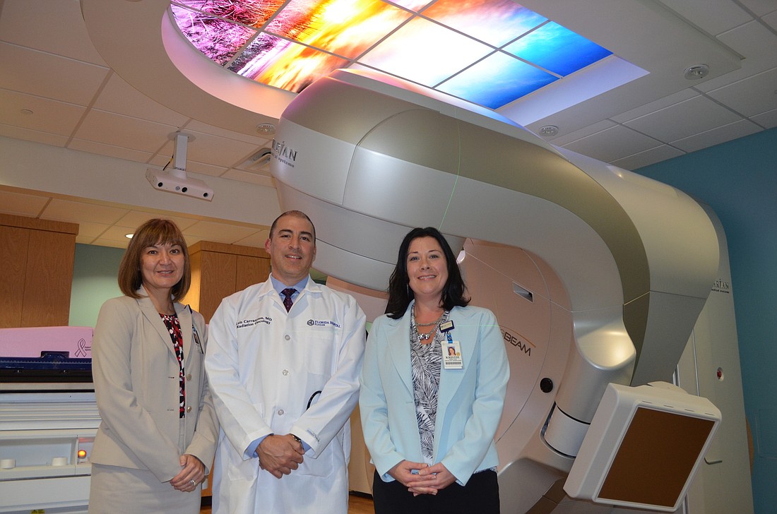 Left to right: Flagler Hospital Florida CEO Joanne King, Radiation Oncologist Luis Carrascosa, and Kristie Reiner, director of oncology operations stand in front of the new treatment machine. Photo by Colleen Michele Jones