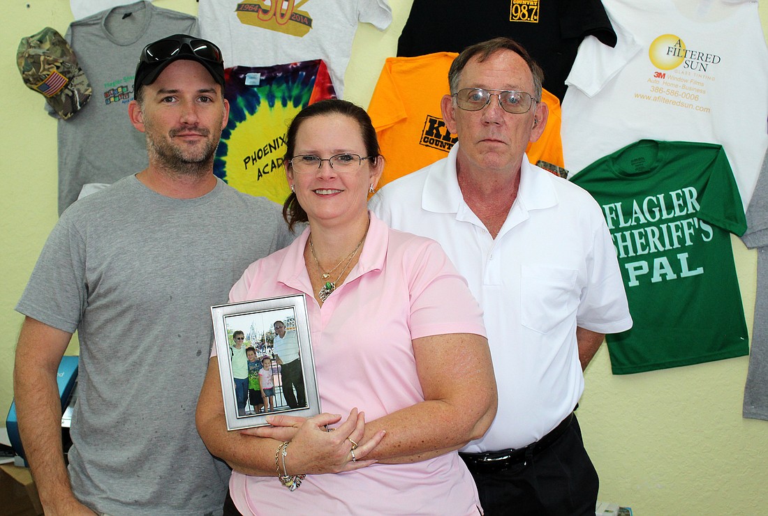 Mark Boos, Kelly Wise-Chapman, and Robert Boos have formed a Foundation in memory of Kathy Boos. Wise-Chapman is holding a family photo. Photo  by Jacque Estes