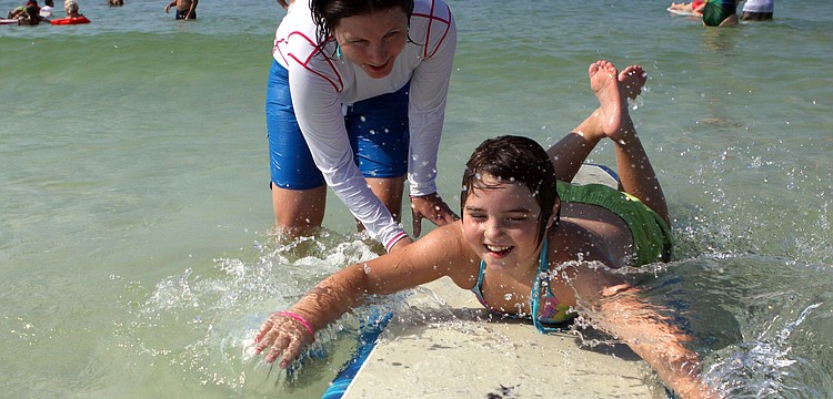 Michelle Stauffer helps Molly Pyrott, 7, during the Hang Ten for Autism surf event Saturday, Sept. 17, at the Siesta Key Public Beach.