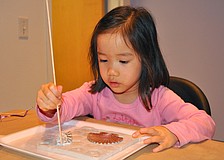 Hannah Smith, 3, puts decorative, little holes into her clay slab.