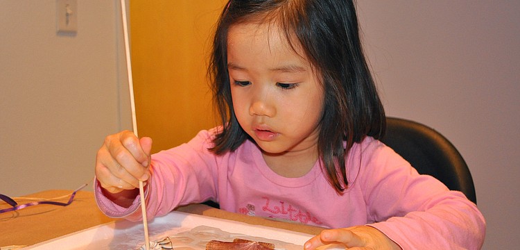 Hannah Smith, 3, puts decorative, little holes into her clay slab.