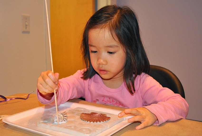 Hannah Smith, 3, puts decorative, little holes into her clay slab.
