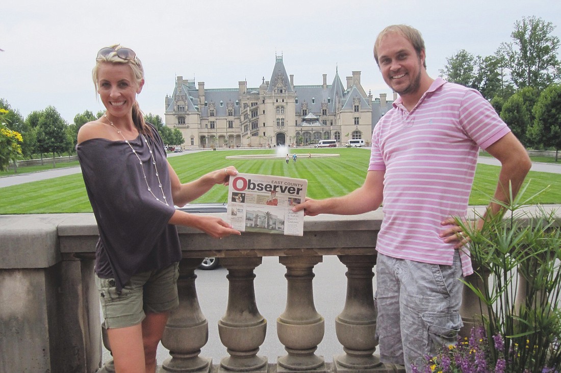 Ashley and Tim Gruters pose with their Observer newspaper in front of the Biltmore estate in Asheville, N.C. Courtesy photos.