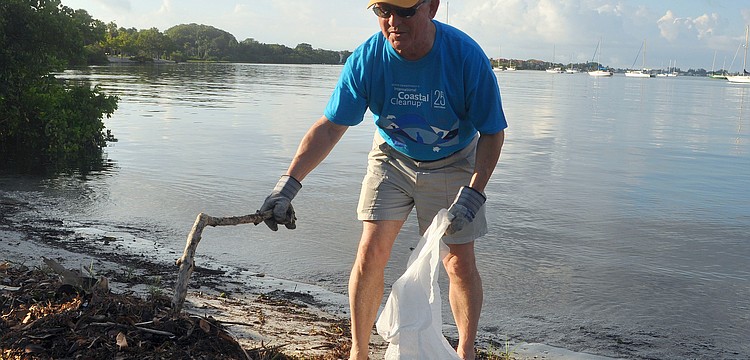 Robin Adair uses a stick to try and find some trash among the brush and seaweed along the shore at Bayfront Park Saturday, Sept. 24, during the International Coastal Cleanup.