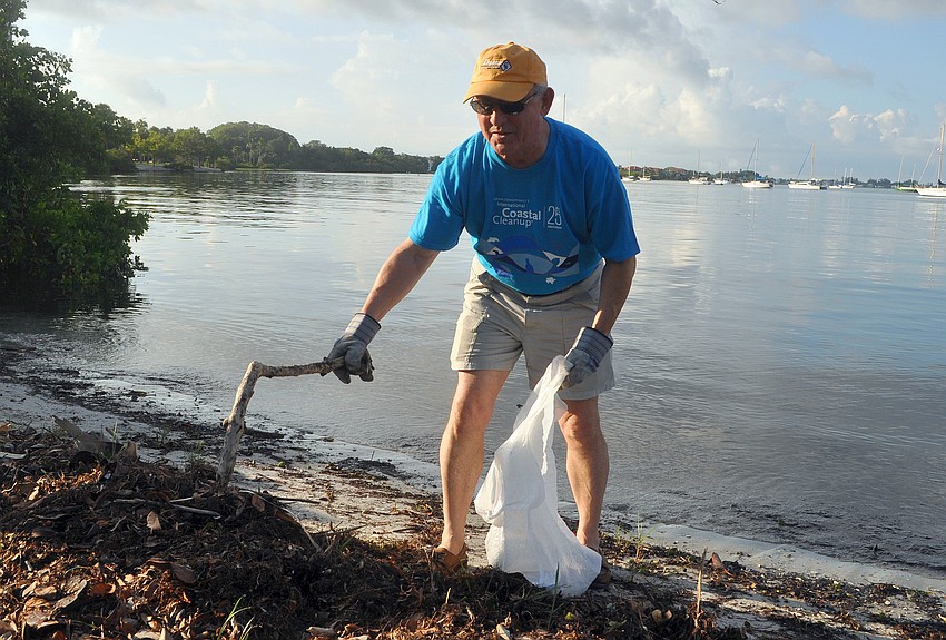 Robin Adair uses a stick to try and find some trash among the brush and seaweed along the shore at Bayfront Park Saturday, Sept. 24, during the International Coastal Cleanup.